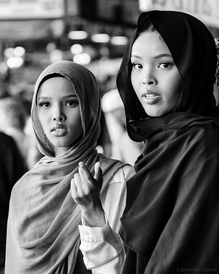 Black and white photo of two women, each wearing a shayla.  One woman is pointing.