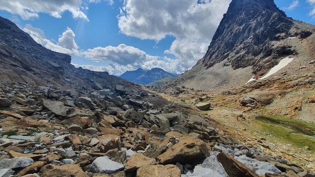 Foto einer Berglandschaft. Es zeigt den Passo della Rossa mit seinem roten Gestein. Rechts ein Gipfel.