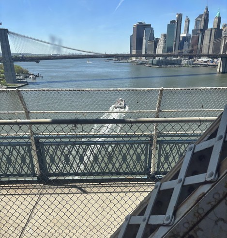 NYC Q train, crossing the river into Brooklyn, a view of another bridge, from my subway car. A boat is seen directly below us heading south.