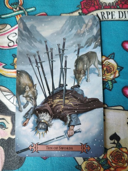 Card from the Modern Spellcaster's Tarot deck.
Ten of Swords.
A man on the ground, face down, dead most likely, with swords driven into his back, holding a sword on the left hand. It is snowing, and two wolves are sniffing him.