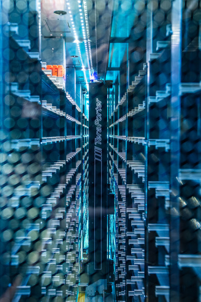 Inside of one of the server rows showing some populated tape media, with a tape drive robotic arm in the center of the image.