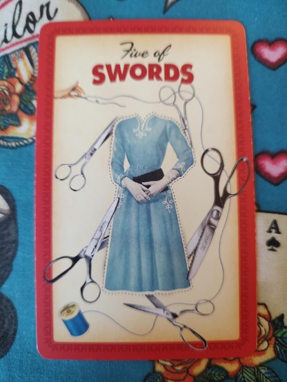 Card from the Housewives Tarot deck.
Five of Swords.
A photo of a woman's dress pattern, surrounded by scissors and rolls of thread.