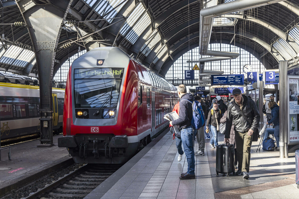 Personen warten auf dem Bahnsteig auf Halt des Einfahrenden Zuges
