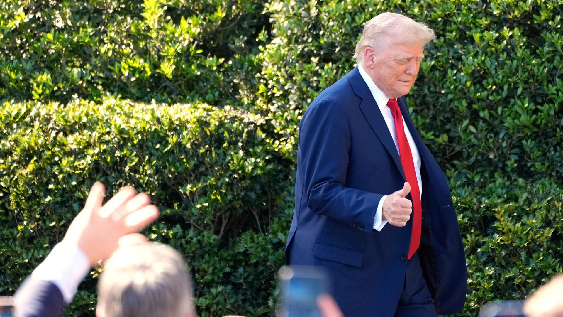 Präsident Donald Trump verlässt eine Pressekonferenz und geht am Publikum mit der Geste des erhobenen Daumens vorbei.