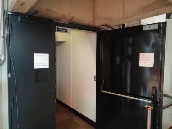 Porte ouverte avec un panneau "maintenir fermée" dessus.