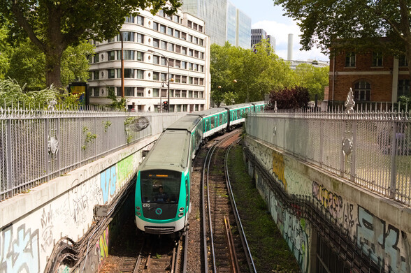 Sur un arrière-plan composé d’immeubles et de verdure, une double voie de métro en courbe apparaît dans une tranchée. Sur la voie de gauche (du point de vue de la photo), une rame du métro parisien, de type MF01 (la rame numéro 070 très précisément) nous fait face. Une fois n’est pas coutume, sa girouette indique « République », et non pas « Bobigny » : en effet, ce jour-là, en raison de travaux, la ligne est coupée entre République et Gare du Nord.