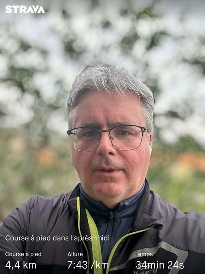 Une personne prenant un selfie avec des statistiques d'exercice de Strava indiquant une course de 4,4 km en 34 minutes et 24 secondes.