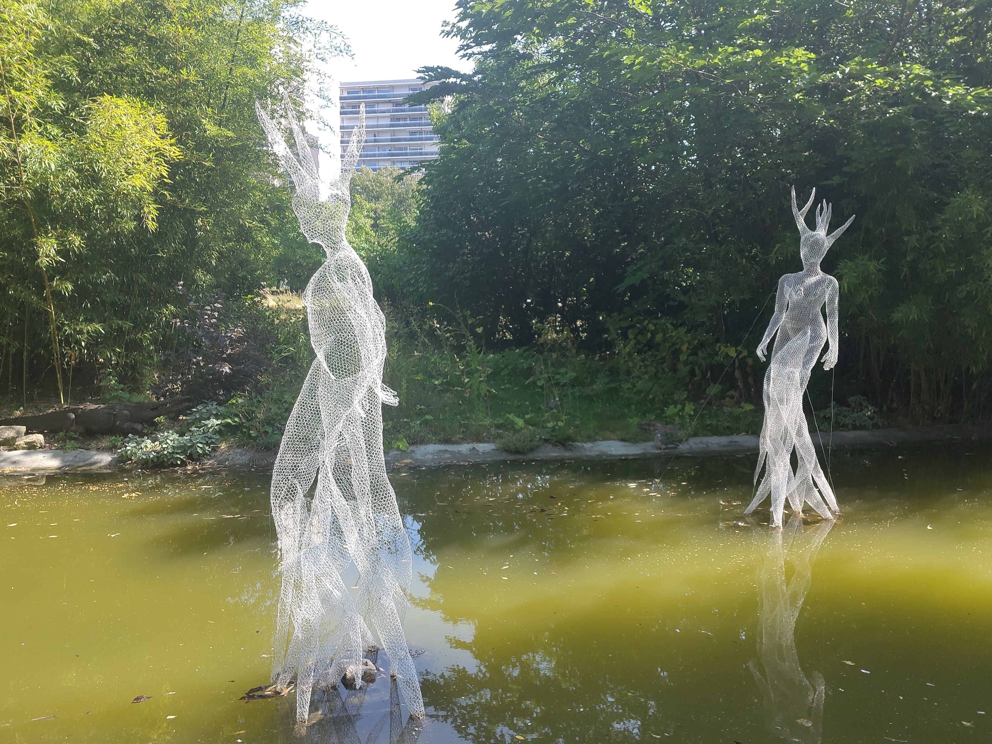 Deux sculptures de personnages humanoïdes plutôt féminins avec des cornes/branches sur la tête et à pieds-racines)