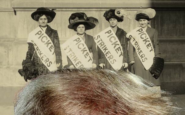 Four turn-of-the-century women strikers, bearing sashes reading PICKET STRIKERS. In the foreground is an extreme magnification of the top of Trump's hair.