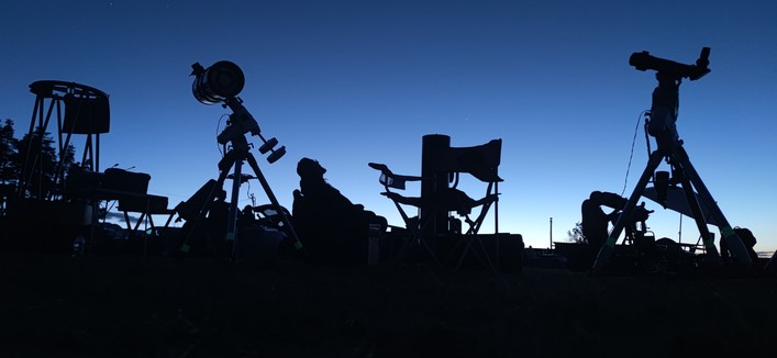 Un crépuscule magnifique, des instruments d'observation en ombre chinoise, un observateur assis, les yeux vers le ciel.