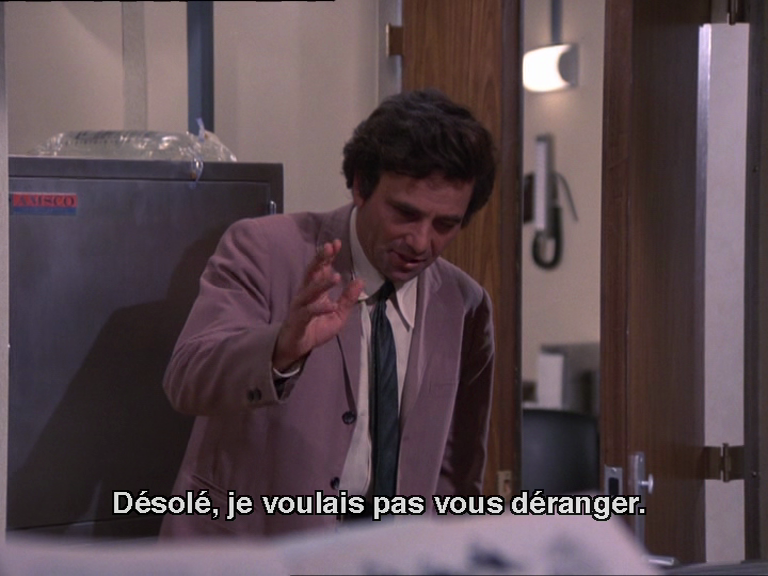 Columbo dit "désolé, je voulais pas vous déranger" il porte un costume exquis, une veste dont le gris tire sur la vigne, une chemise subtilement crème, et une cravate au vert profond quasi noir