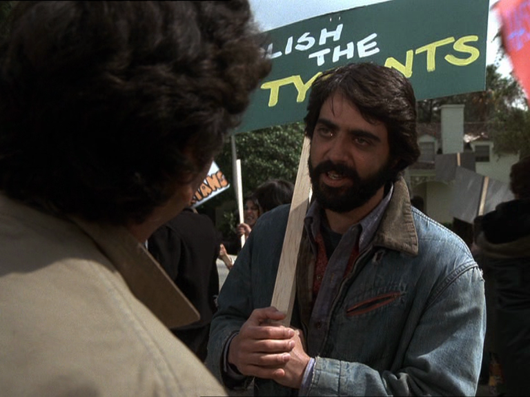 un homme barbu brun au cheveu lisse et brillant en tout point similaire à fabrice arfi parle à columbo en tenant une pancarte "Abolish The Tyrants" un homme barbu brun au cheveu lisse et brillant en tout point similaire à fabrice arfi parle à columbo en tenant une pancarte "Abolish The Tyrants"