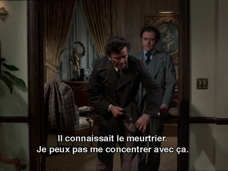 Columbo en train d'enlever son nouveau pardessus sombre.
Sous-titre : "je peux pas me concentrer avec ça"