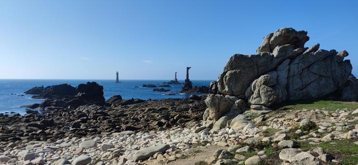 Le phare et ses deux pylônes à marée basse. Ciel bleu mer d'huile