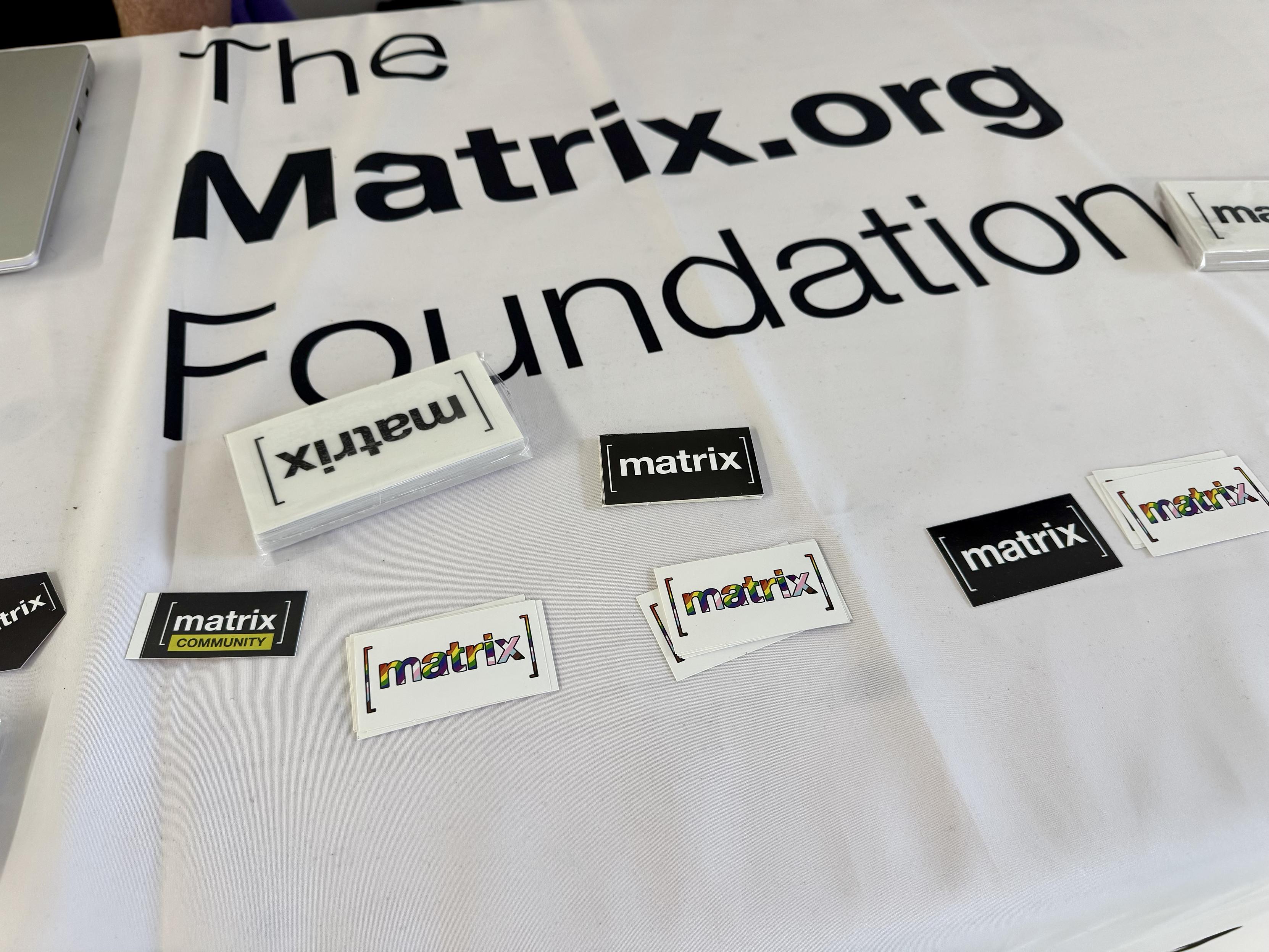 A photo of a table with stashes of stickers including ones with the colors of the progress flag
