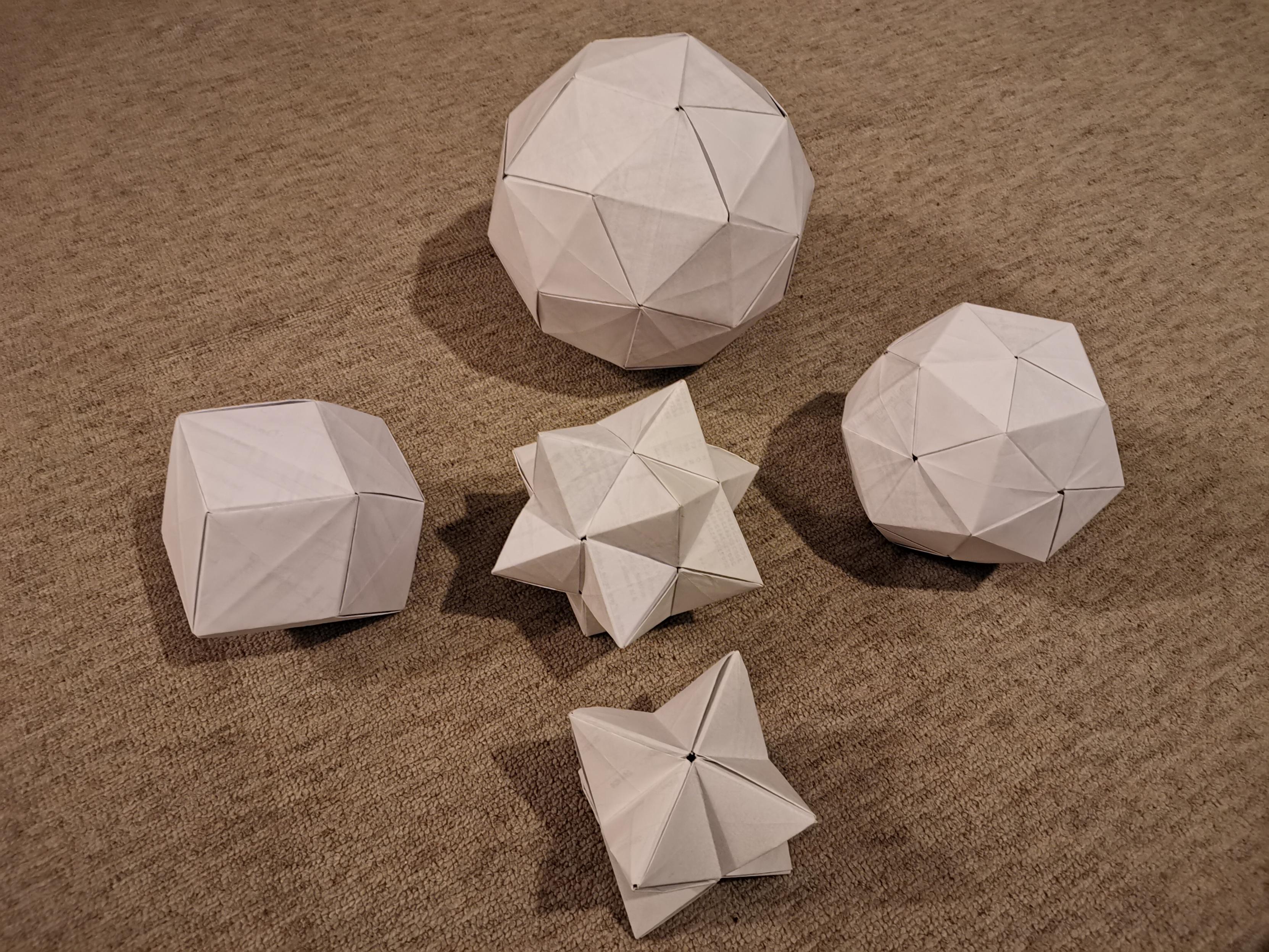5 pliages en forme de polyèdre réalisés à partir de plusieurs feuilles de papier.
C'est à dire des origamis modulaires.
Photo extraite de https://multicristo.blogspot.com/2021/11/exemples-dorigamis-modulaires.html