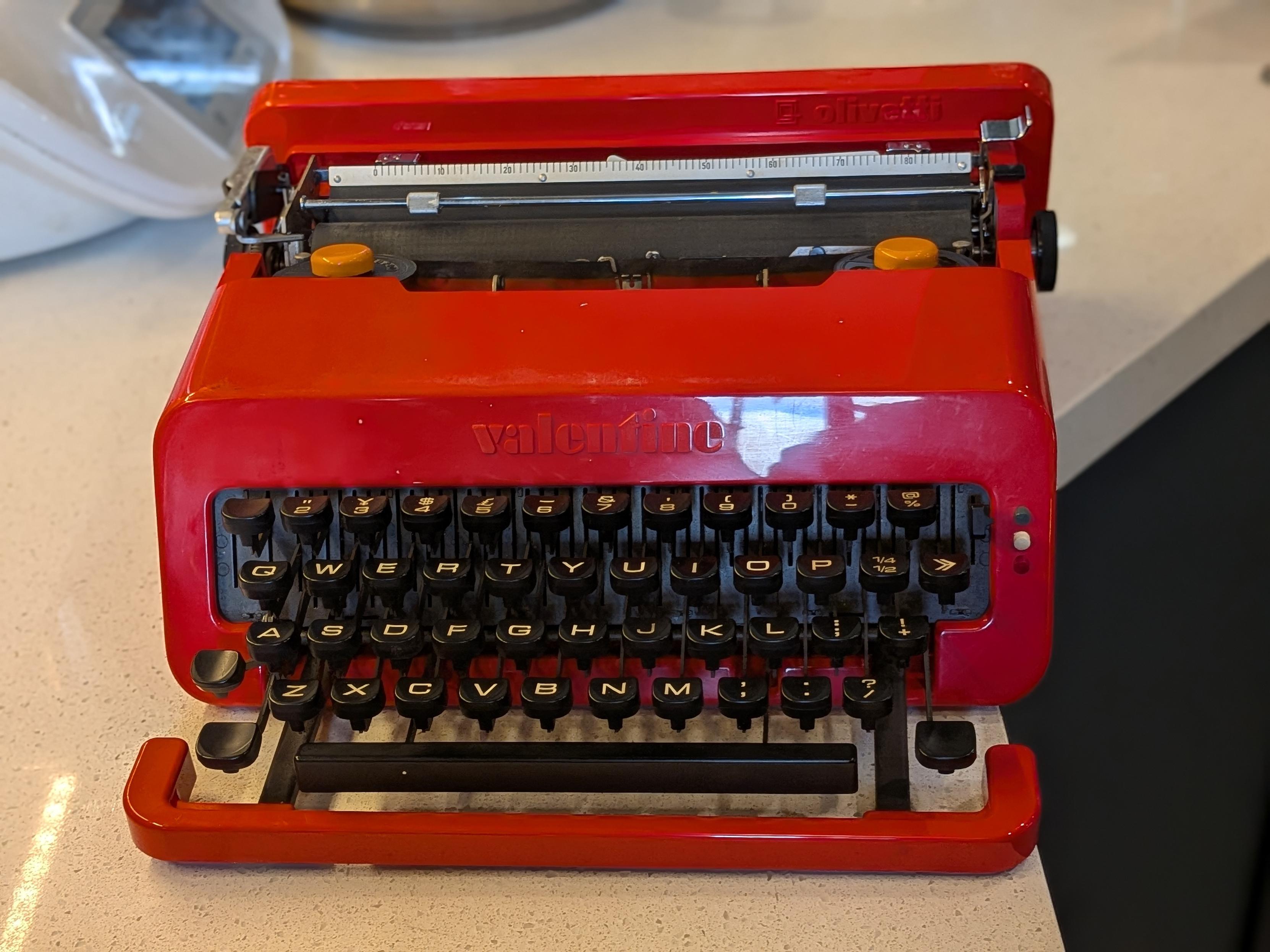 A red, injection-molded ABS plastic Olivetti Valentine portable manual typewriter from 1969.