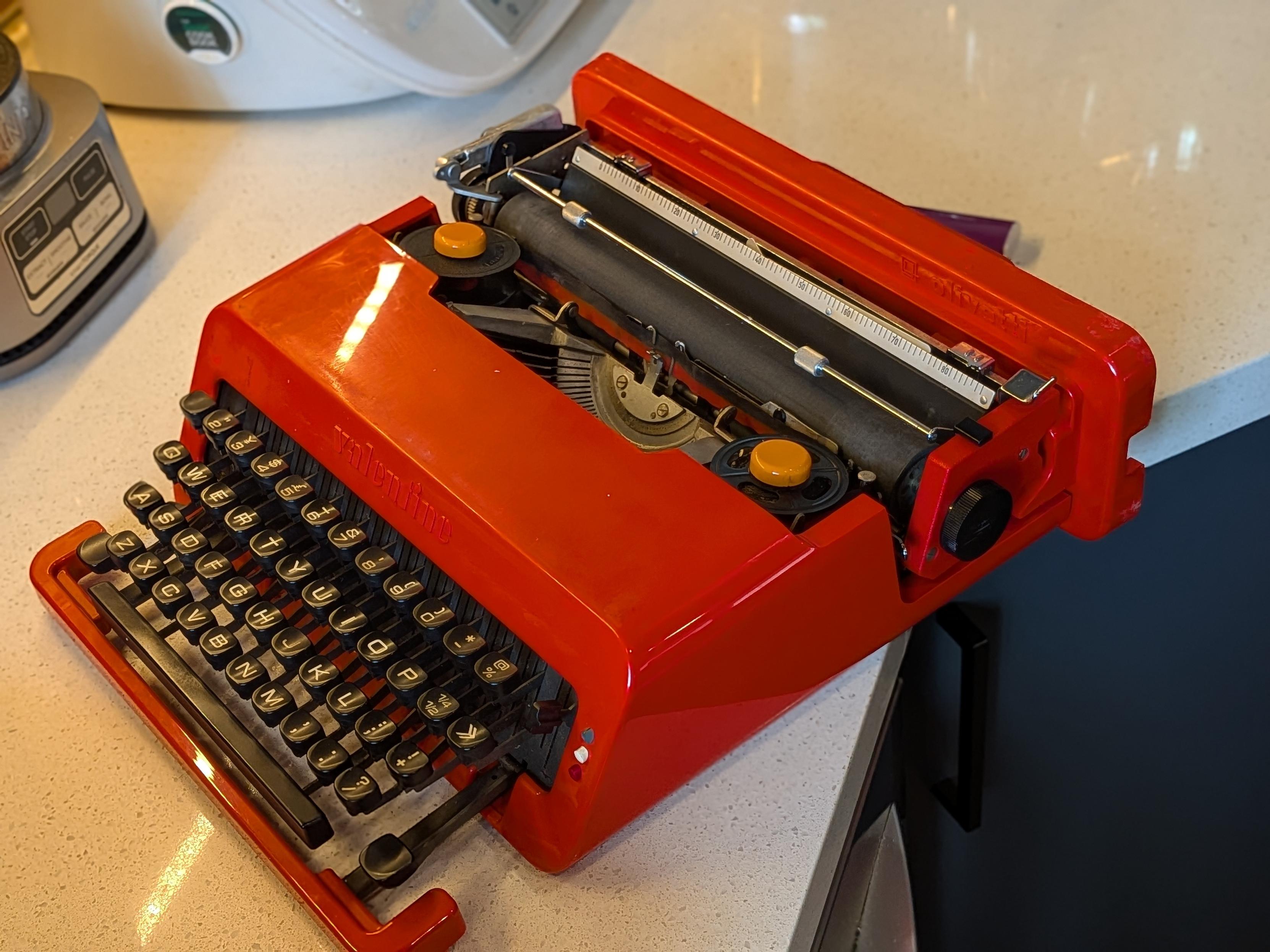A red, injection-molded ABS plastic Olivetti Valentine portable manual typewriter from 1969.