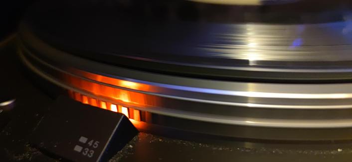 Platine disque en fonctionnement, une lampe néon orange éclaire le stroboscope pour contrôler la régularité de la vitesse du disque.
