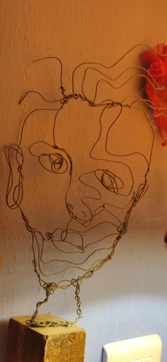 sculpture en fil de fer sur un support en bois. Mon portrait, réalisé par une de nos amies chères, Élise Shootthelife, de son nom d'artiste. Pas encore sur le fédiverse malheureusement.