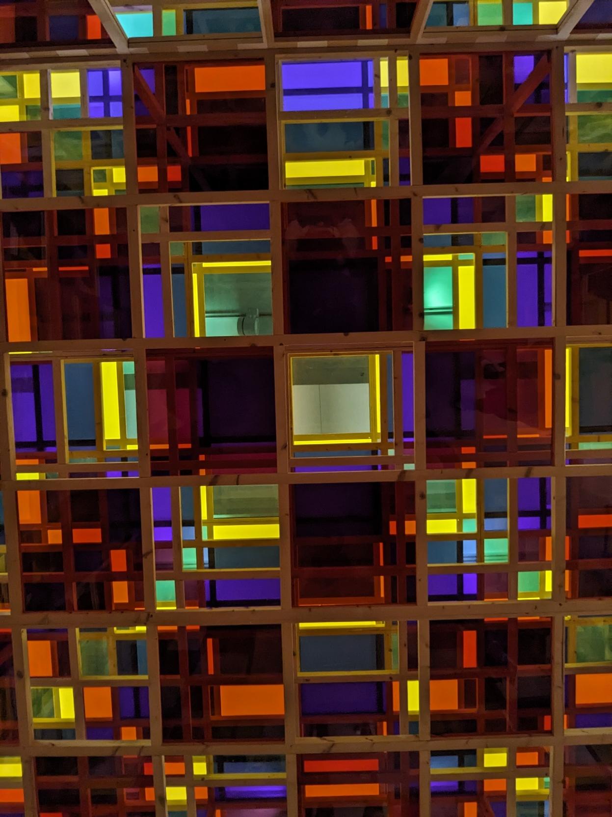 L'intérieur d'une cabane de Buren, installation consistant à superposer dans les trois dimensions des carrés translucides cyan, magenta et jaunes.
La photo représente l'intérieur quand on regarde en haut