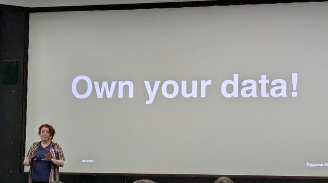 Charlie O'Hara in front of a screen reading "own your data!"