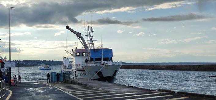 embarquadère d'Audierne pour l'île de Sein. l'Enez Sun en plein chargement de containers. le temps de ce matin est incertain, ciel bleu avec des averses
