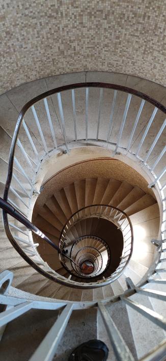 escalier en colimaçons dévoilant le vide central du phare. photo prise près du sommet.