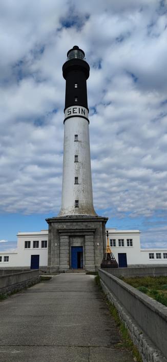 Phare du Goulenez se dressant majestueusement sur l'île de Sein. Nuages moutonnants sur fond de ciel bleu
