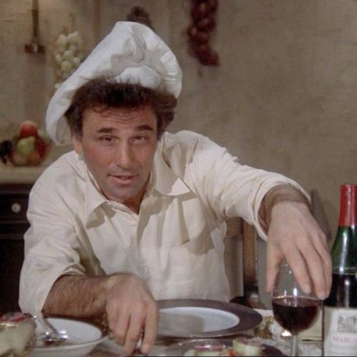 Columbo en chemise blanche avec une toque de cuisine blanche penchée sur sa tignasse ébourriffée, il a un verre de rouge à la main et l'oeil de celui qui s'apprête à niquer un méchant