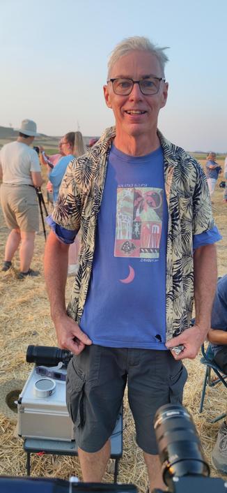 Homme heureux et béat en chemisette et t-shirt, ce dernier étant une relique d'une précédente éclipse en Zambie en 2001. Sur le t-shirt, un croissant de soleil orangé.et l'image projetée vient d'une petite lunette astro sans filtre solaire dirigée vers le t-shirt. Attention ! Ne jamais mettre l'œil à l'oculaire d'un instrument pointé vers le soleil s'il n'est pas muni d'un filtre adapté !
 cascade réalisée par un astronome amateur, à ne pas réaliser chez soi sans connaissance préalable.