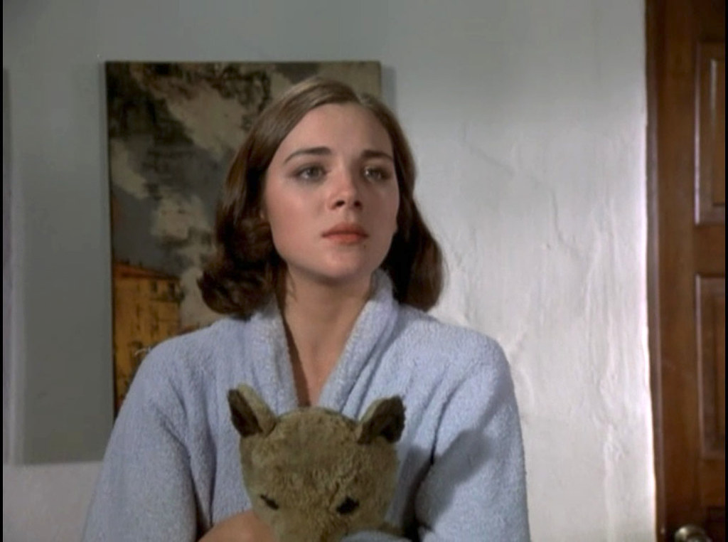 photogramme de Columbo : Kim Cattrall en robe de chambre, très jeune et châtain, serre un ours en peluche dans ses bras.