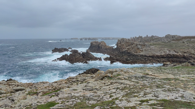 panorama au pied du phare du Creac'h par une mer un peu agitée. les vagues s'écrasent sur les rochers très découpés. le ciel est gris. et le son lancinant et continu d'essoreuse géante...