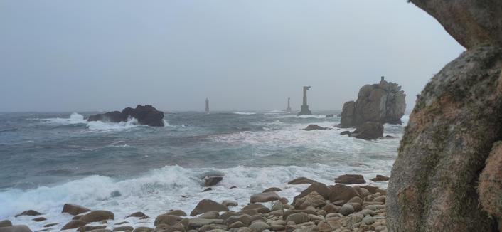 le phare de Nividic et ses deux pylônes. Mer un peu agitée, pas mal d'écume, temps gris. Photo prise sous une averse à l'abri d'un gros rocher.