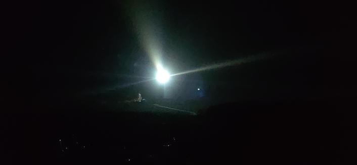 photo de nuit du phare de Creac'h avec ses immenses faisceaux. au pied, éclairé par le phare, l'ancien sémaphore