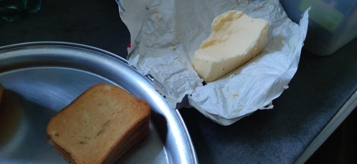 des biscottes qui attendent d'être beurrées, une livre de beurre déjà bien entamée (et aucune en réserve dans le frigo)